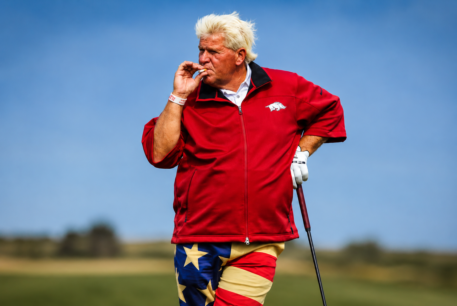 Older man in a red golf jacket and American flag pants standing on a golf course