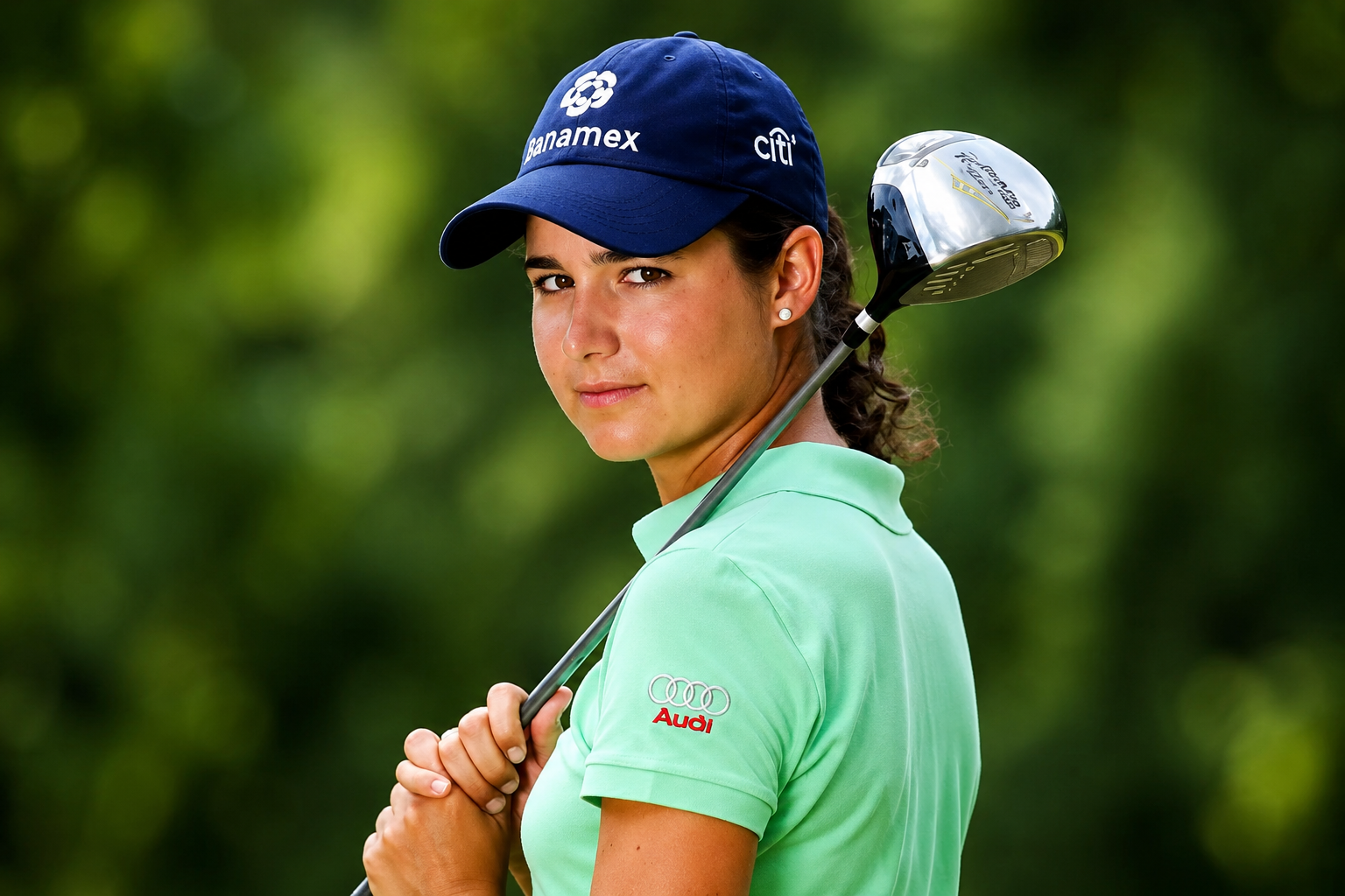Lorena Ochoa posing with a golf club in a mint green polo shirt