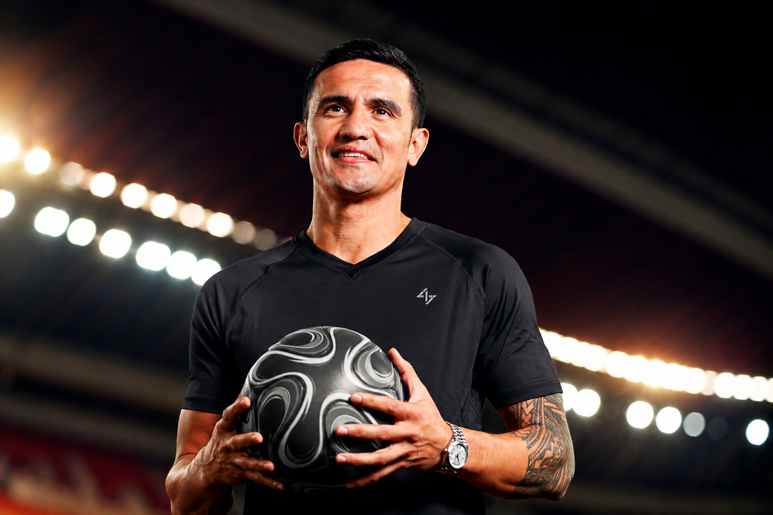Tim Cahill holding a soccer ball in a stadium