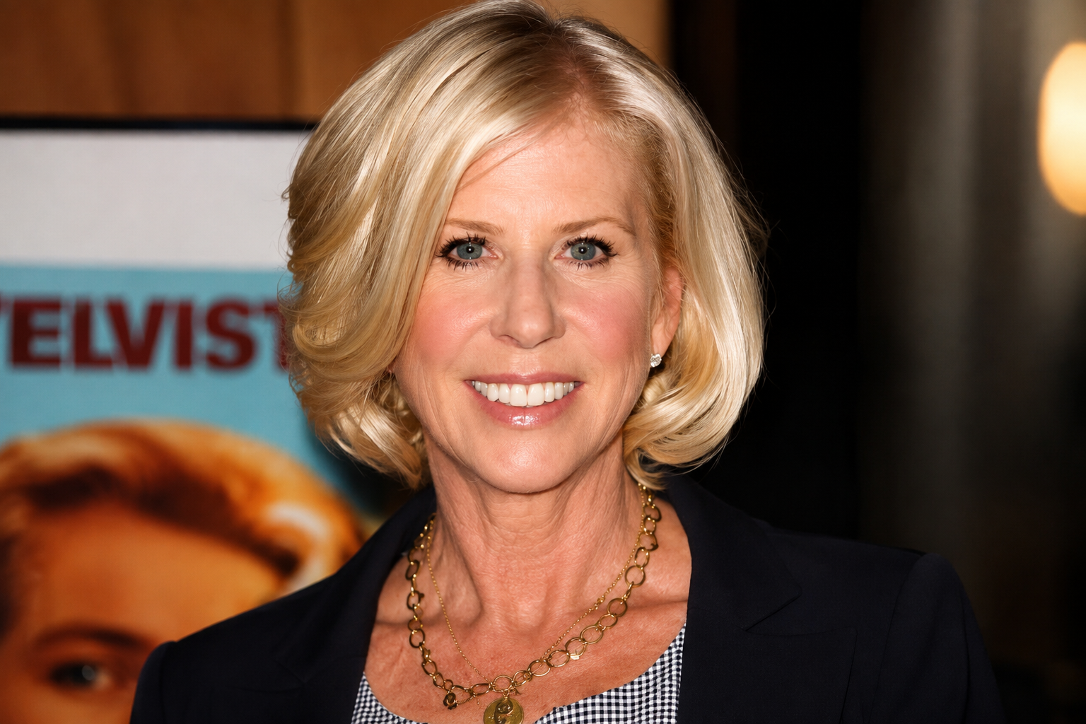 Callie Khouri smiling at a public event in a black blazer and gold necklace