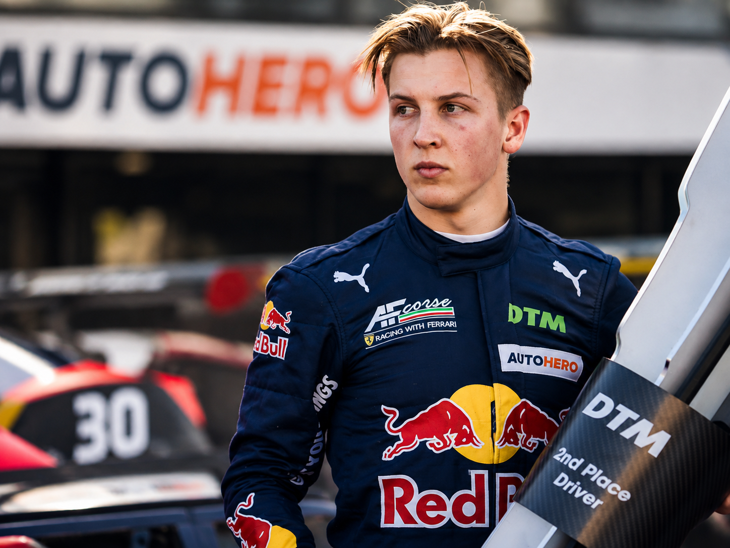 Liam Lawson wearing a Red Bull racing suit and holding a DTM trophy