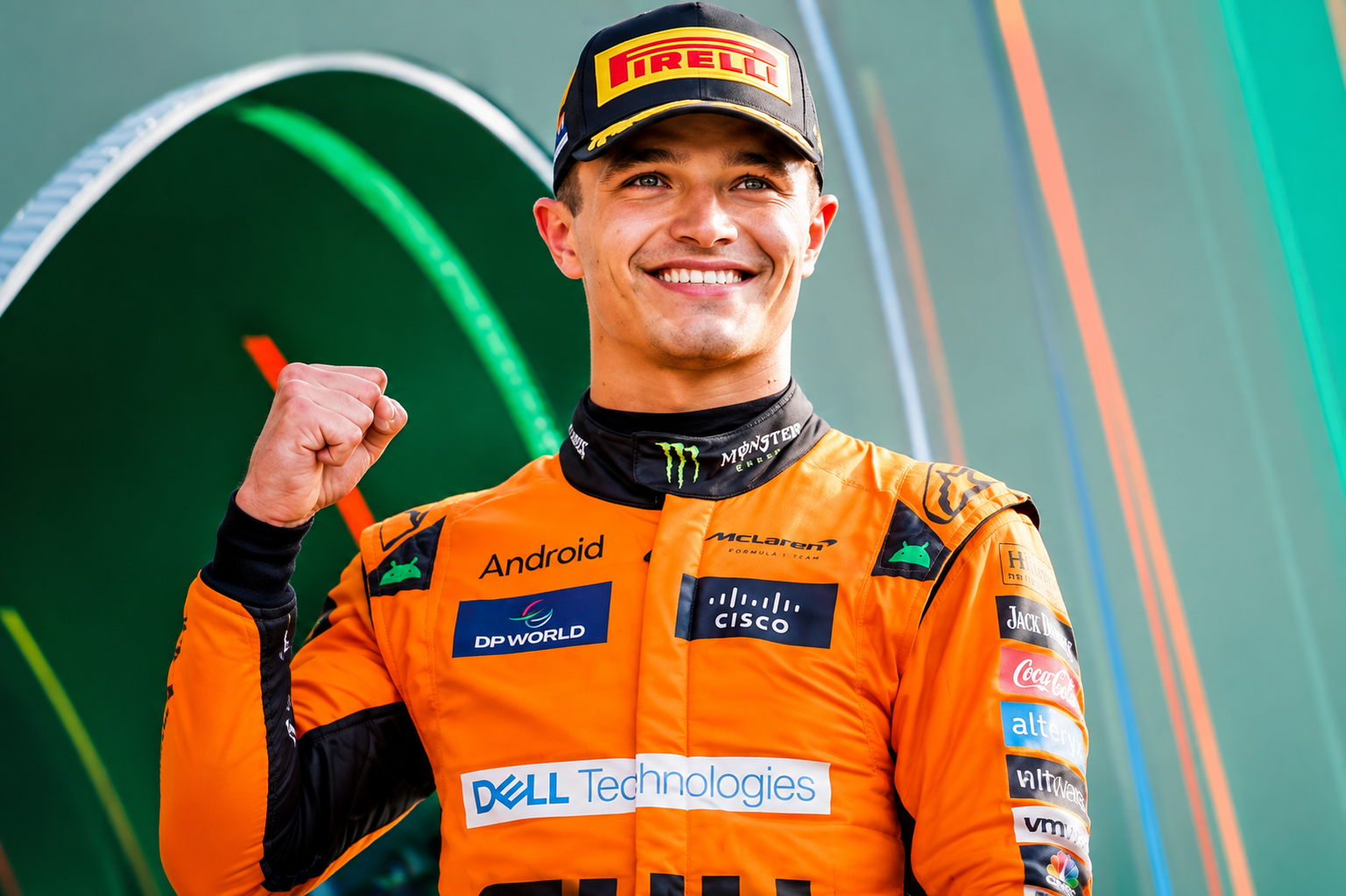Lando Norris wearing an orange McLaren racing suit and celebrating with a raised fistc