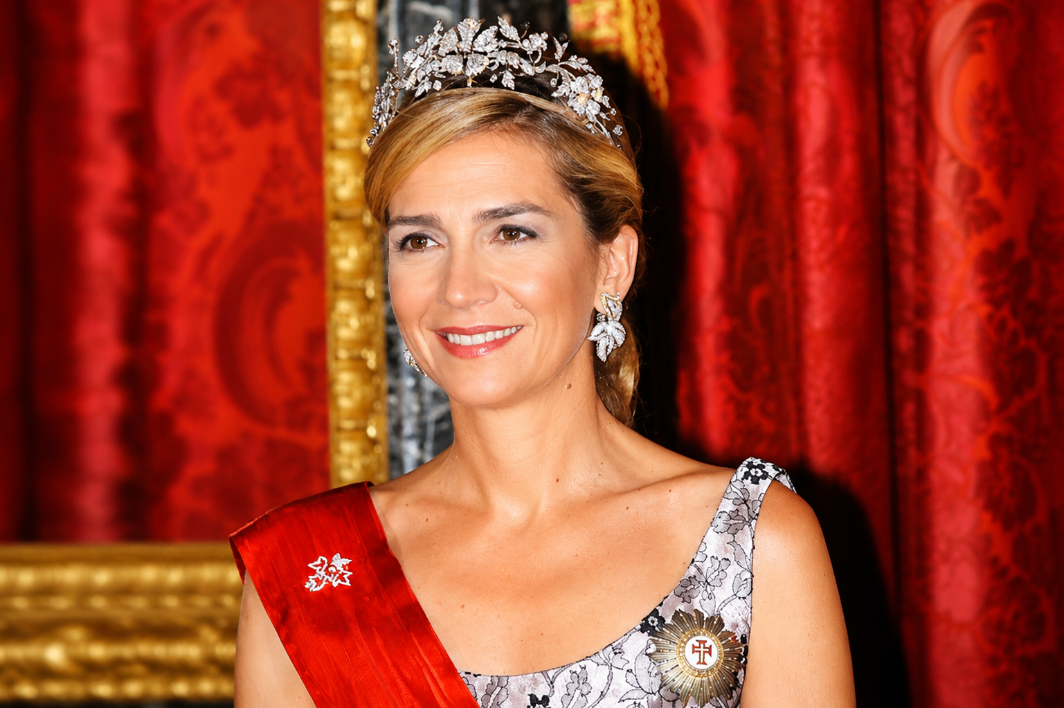 Infanta Cristina wearing a jeweled tiara and red sash in a formal royal portrait