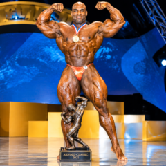 Ronnie Coleman posing on stage with a bodybuilding trophy