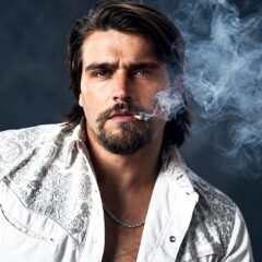 Gavin Adcock posing in a white patterned shirt with smoke in the background