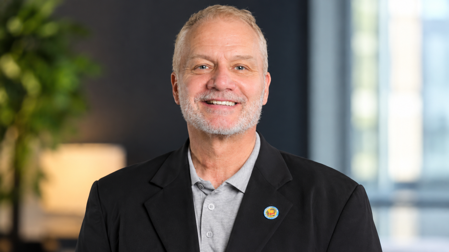 David Tolley net worth 2026 – smiling in a professional portrait wearing a dark blazer and gray shirt