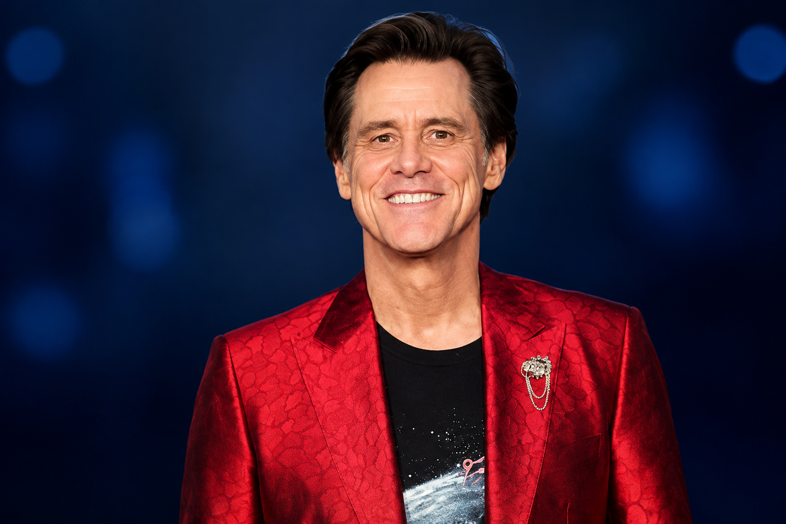 Jim Carrey net worth 2026 – wearing a red blazer and smiling at the camera