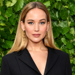 Jennifer Lawrence net worth 2026 – posing in a black blazer with a green leafy background