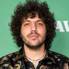 Benny Blanco net worth 2026 – wearing a patterned black shirt and necklaces at a public event