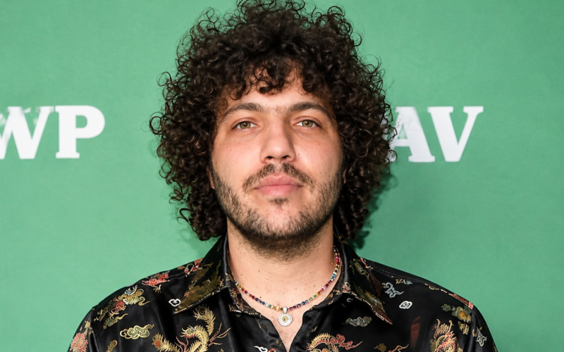 Benny Blanco net worth 2026 – wearing a patterned black shirt and necklaces at a public event