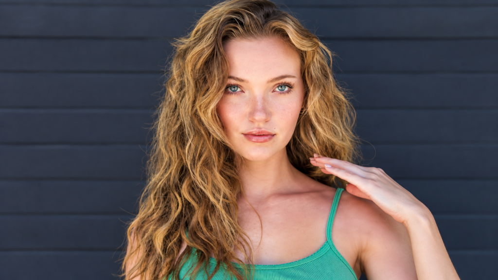 Alyssa McKay net worth 2026 – with long wavy blonde hair wearing a green top