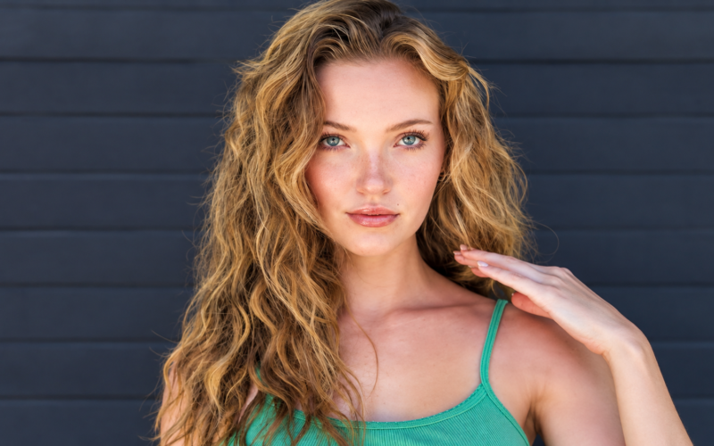 Alyssa McKay net worth 2026 – with long wavy blonde hair wearing a green top