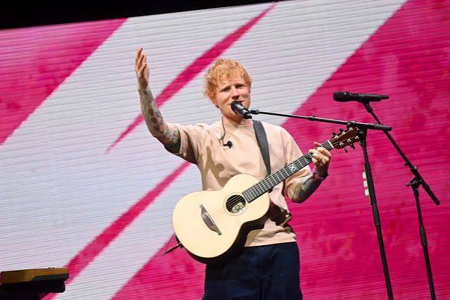 Ed Sheeran performing on stage with an acoustic guitar