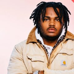 Tee Grizzley posing in a tan jacket with dreadlocks