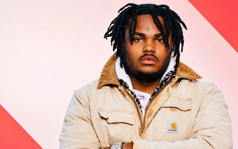 Tee Grizzley posing in a tan jacket with dreadlocks