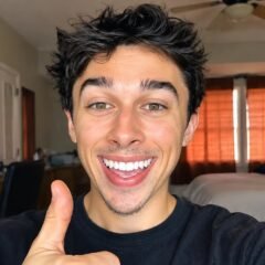 Tyler Vitelli smiling and giving a thumbs-up in a bedroom