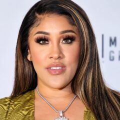 Natalie Nunn with long highlighted hair and a silver pendant necklace at a music group event